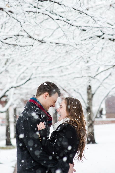 A couple poses for a portrait as snow falls