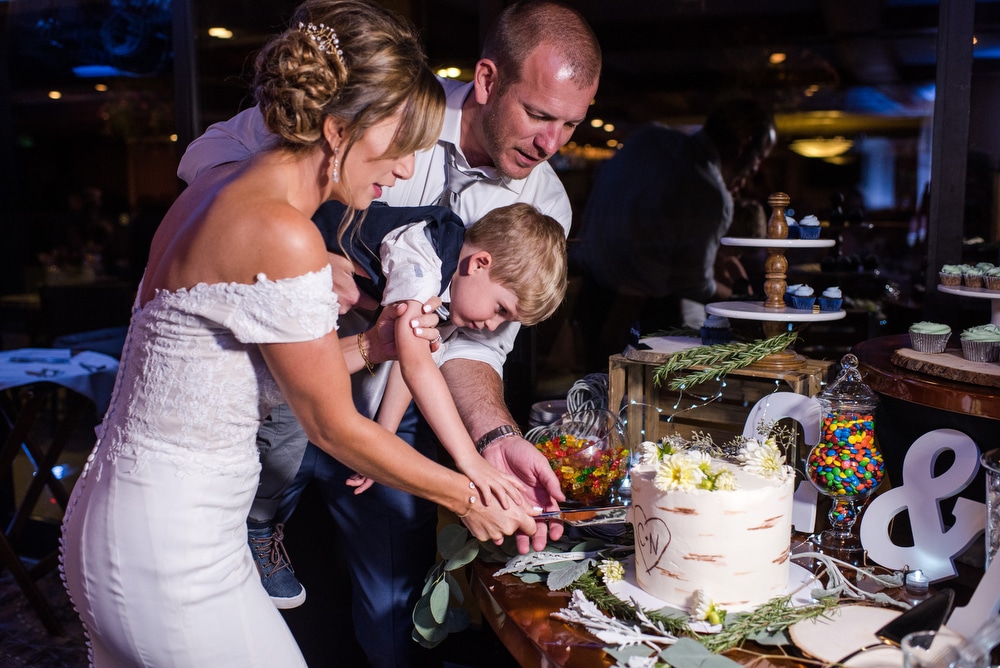 son helps them cut the wedding cake