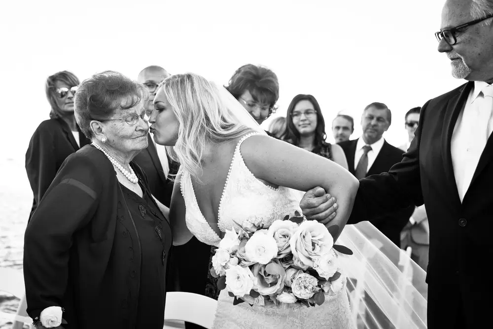 bride kisses grandma as she walks down the aisle