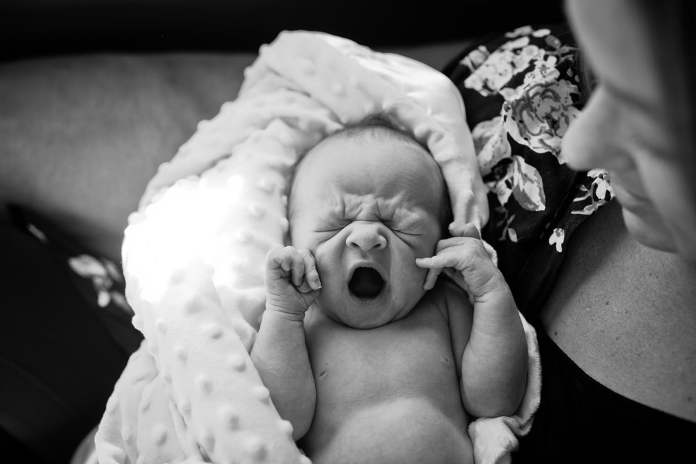newborn baby yawns during her newborn photography session in Denver