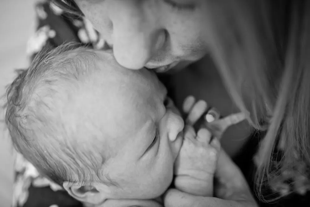 mom kisses newborn baby