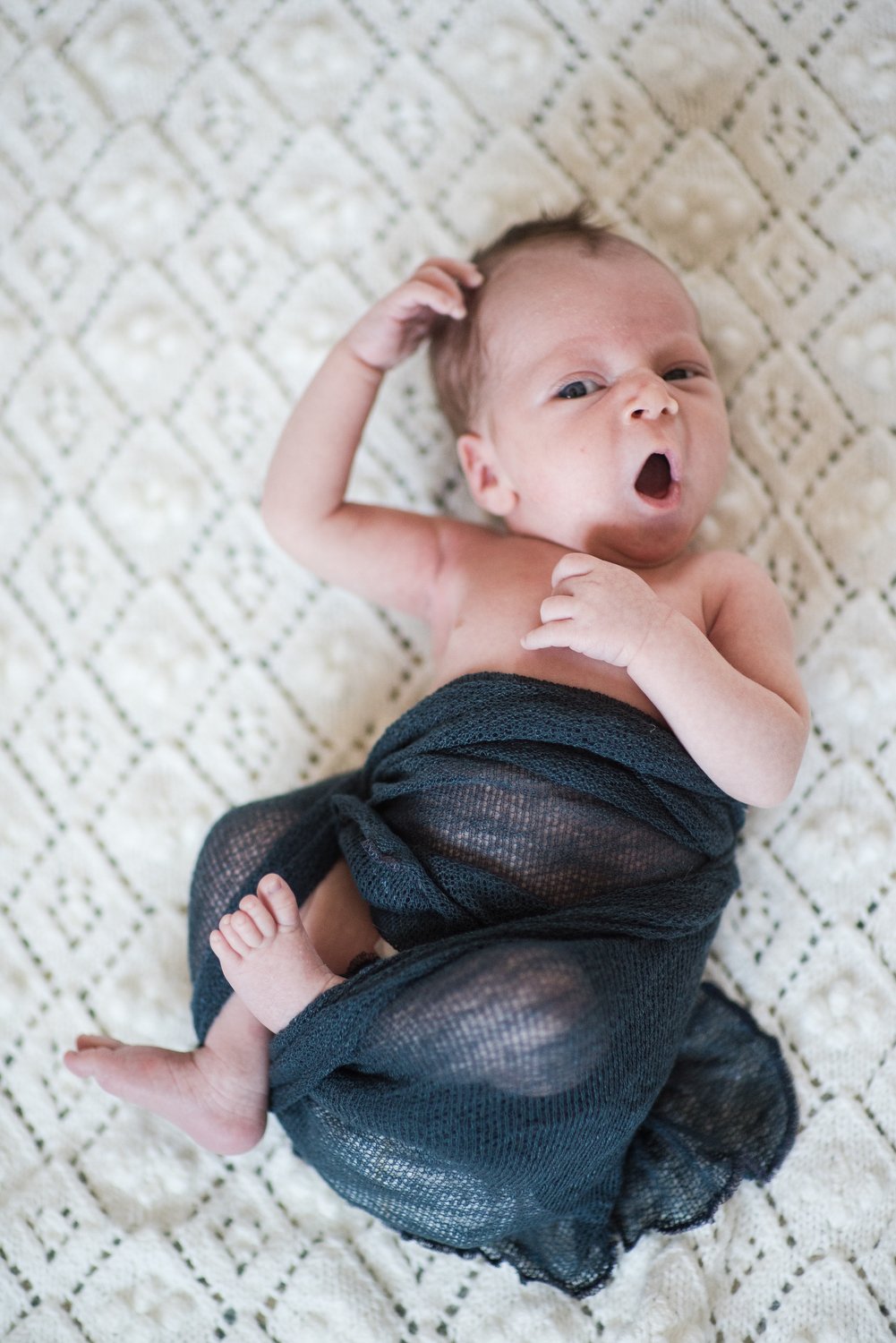 newborn baby yawns as he gets baby photos done in Denver