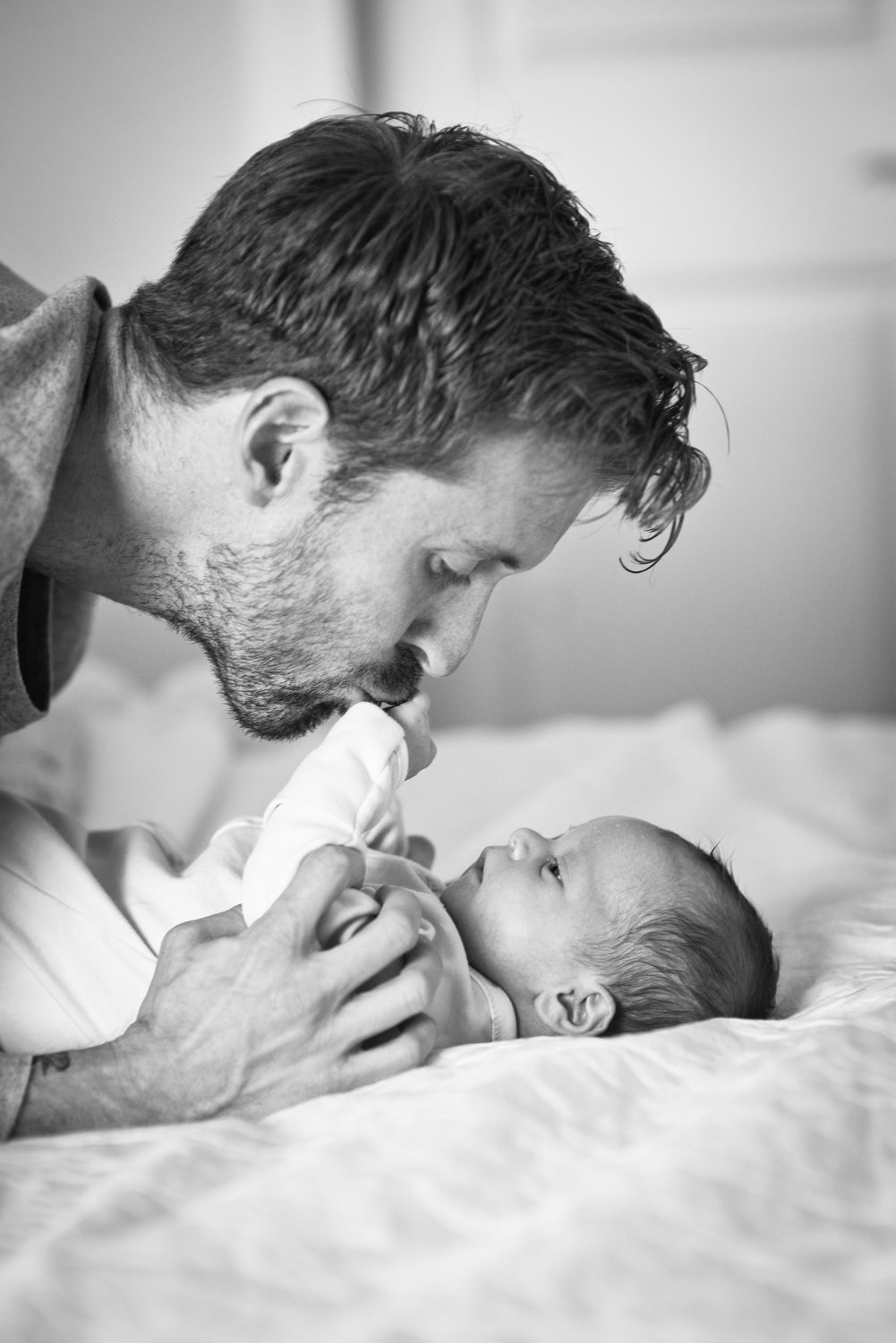 dad kisses his newborn baby boy's hands during portraits