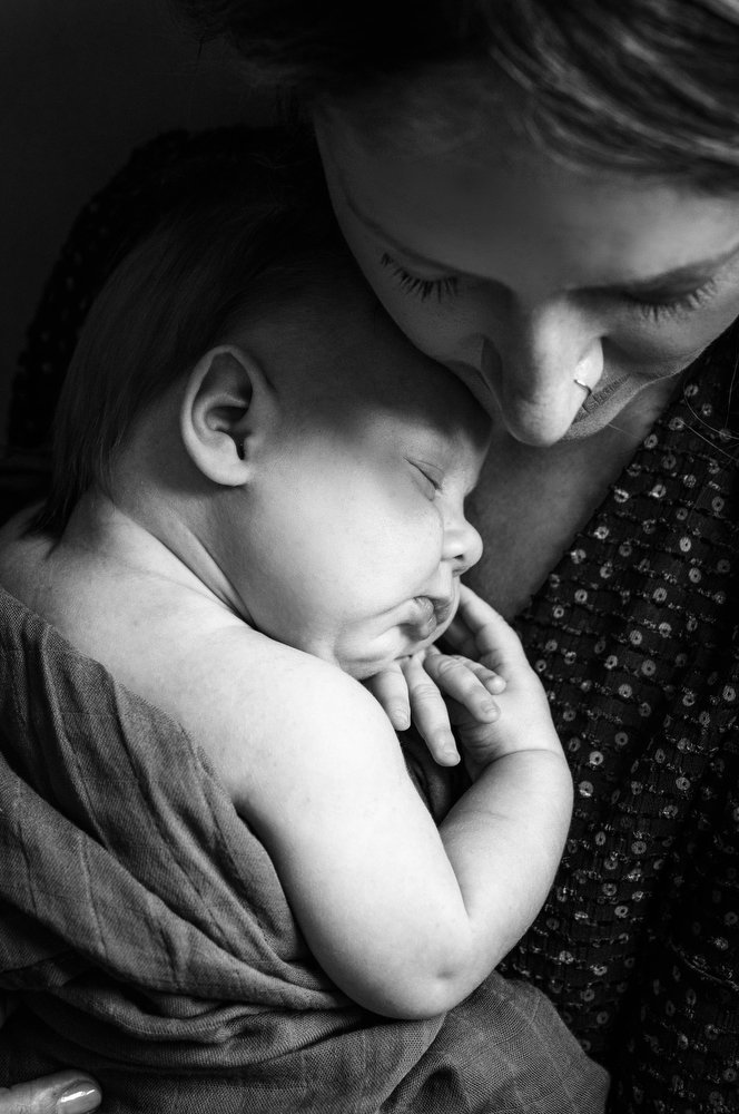 mom snuggles baby girl during newborn portraits