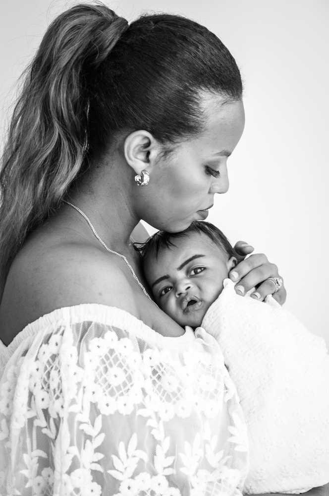 mom in a lacy dress snuggles her newborn baby girl