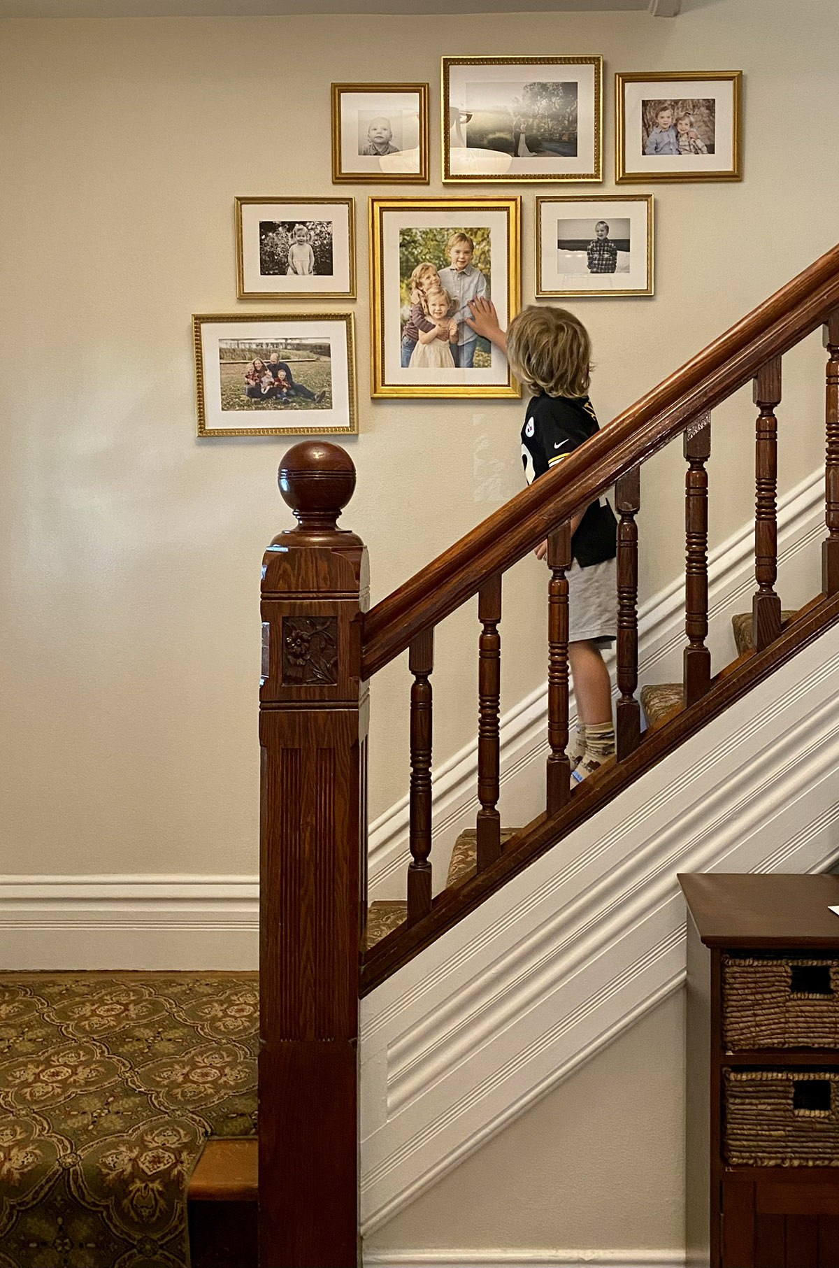 boy looks at framed photos along a staircase
