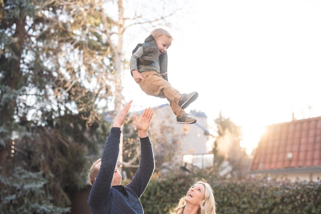 dad throws kid in the air during fun family portrait