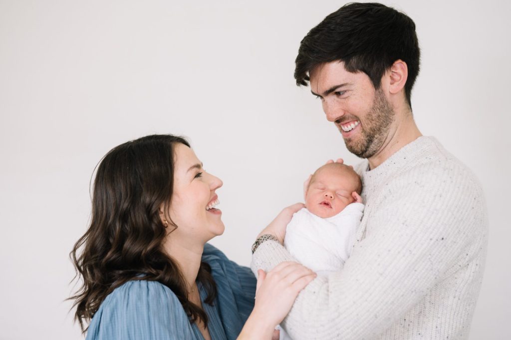couple laughing during newborn portraits in Denver