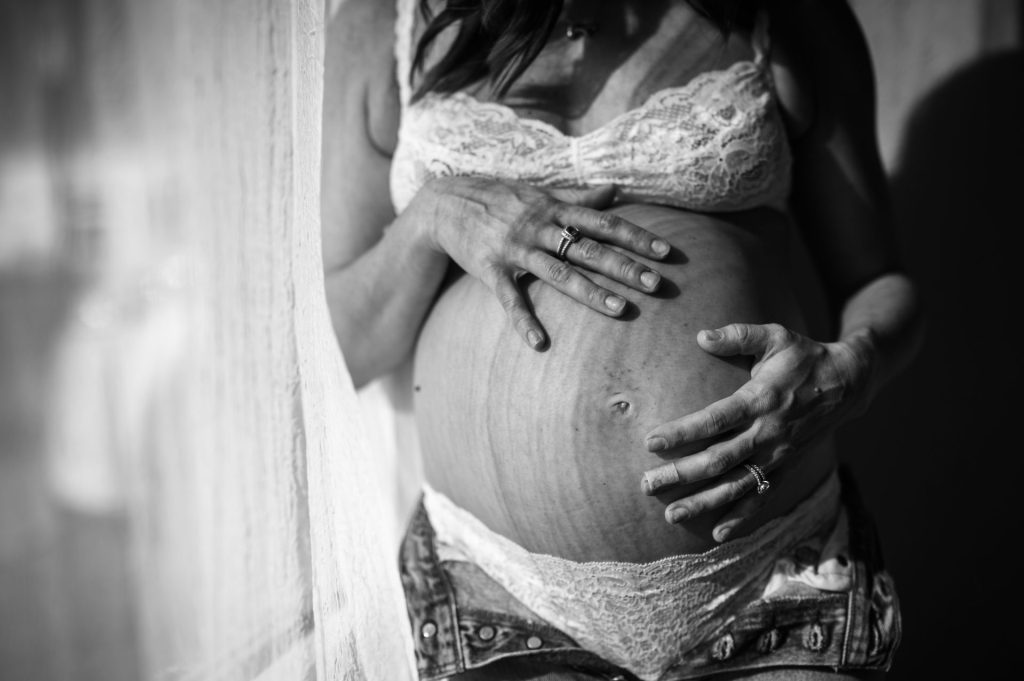 maternity portraits in jeans and a bra in denver