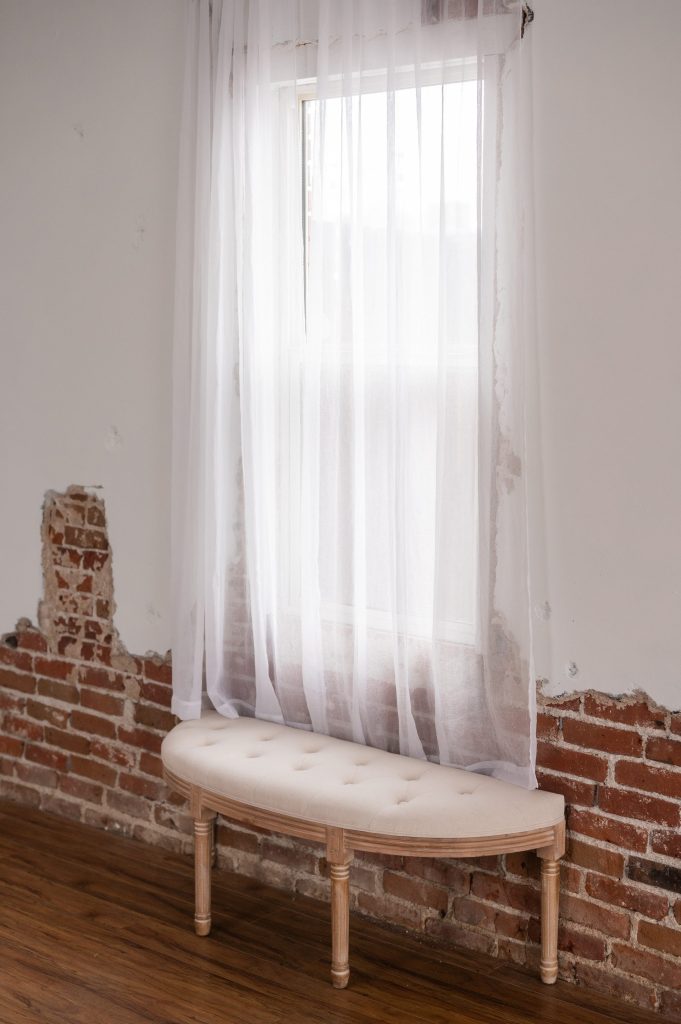 bench in front of a window with a distressed brick wall