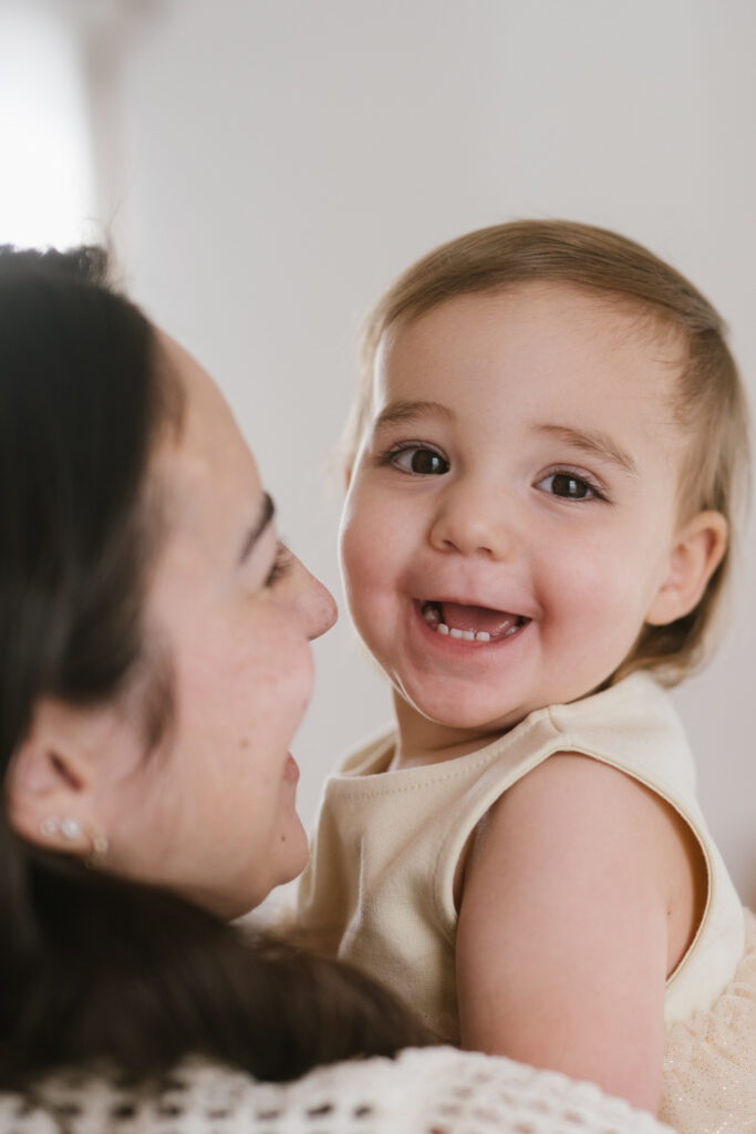 A little girl smiles in her mom's arms.
