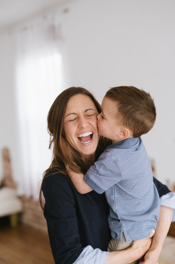 Mom laughs as her son gives her a kiss.