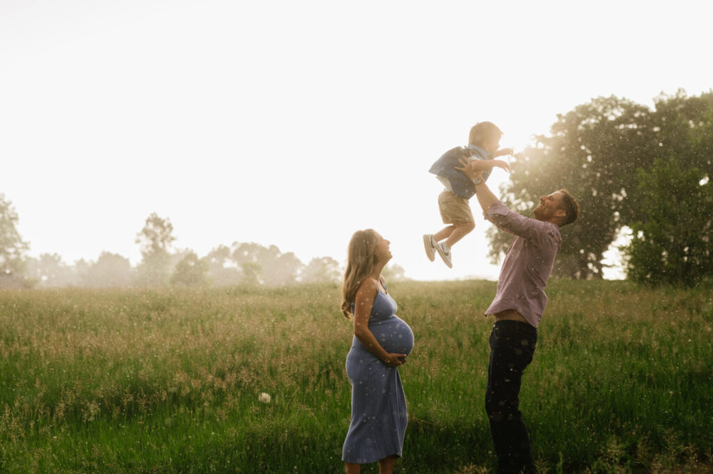 The rain pours as a mom holds her pregnant belly and dad throws their kid in the air during their Denver maternity portraits.