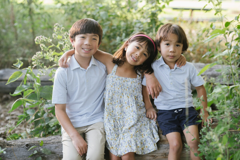 Siblings pose on a log during spring family photos in Denver.