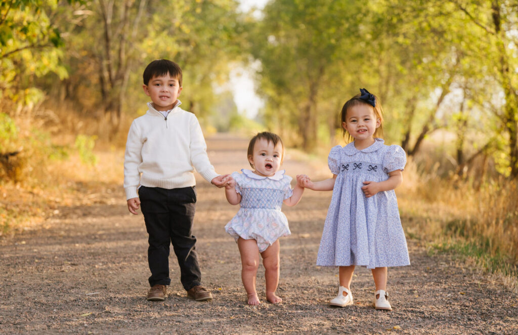 Three little kids hold hands during family portraits in Littleton.