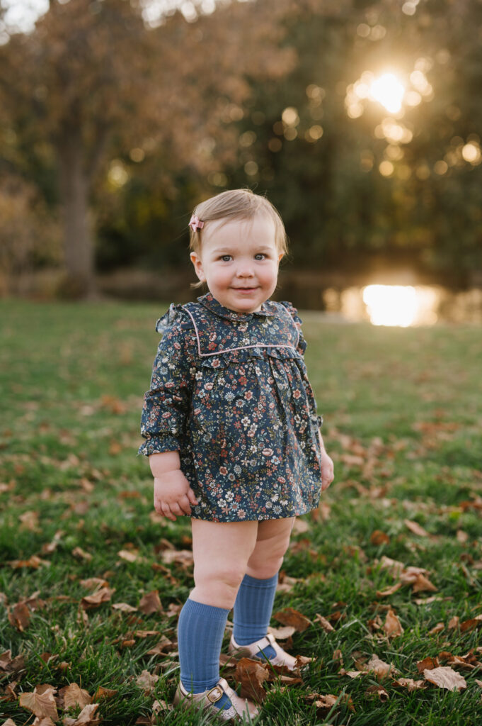 A little girl wearing a romper and knee socks in the fall in Wash Park
