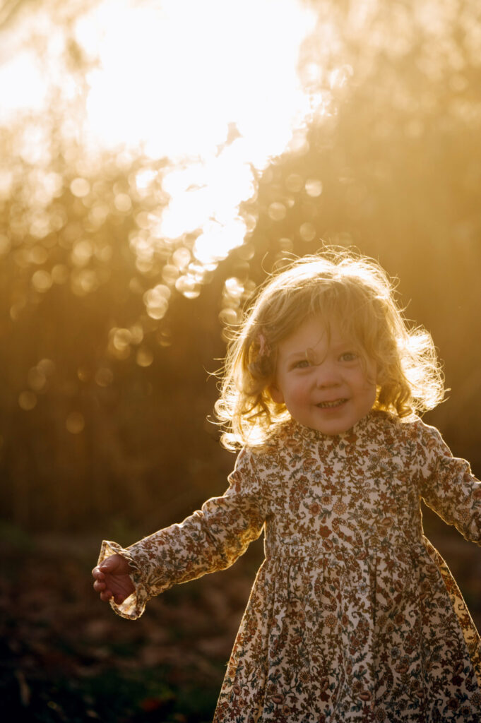 The sun shines behind a girl as she laughs in Denver's Wash Park.