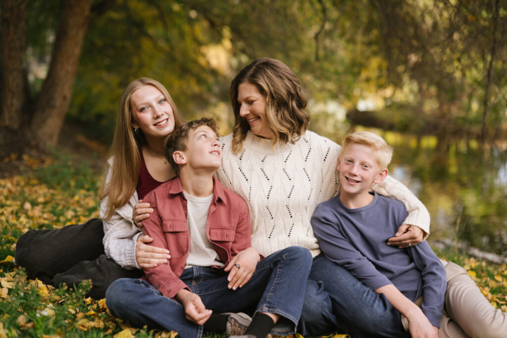 A mom smiles down at her three kids during pictures.