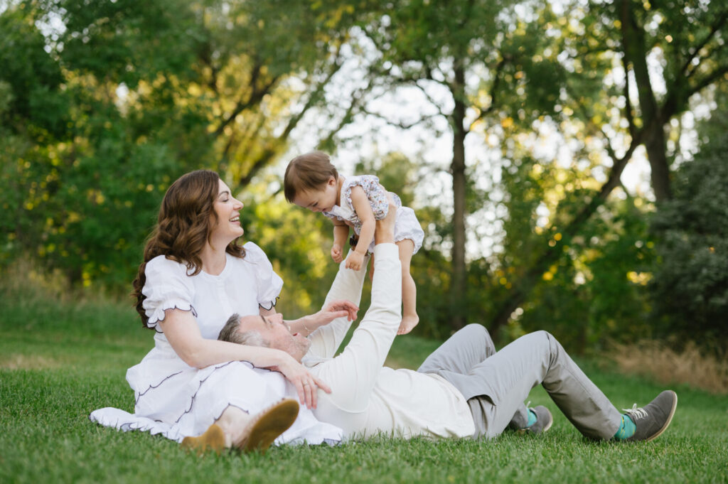 Parents fly their baby girl in the air during spring portraits in Denver.